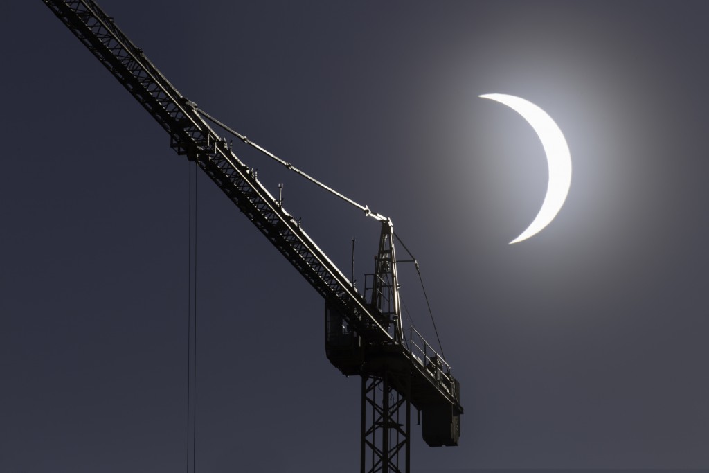Picture of solar eclipse with construction crane in the foreground