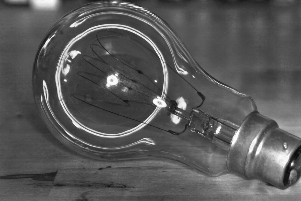 A Black and white shot of a an old carbon filament bulb.