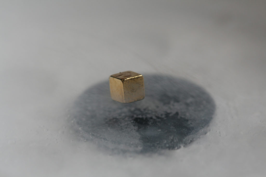 Metal cube levitating over superconducting magnet