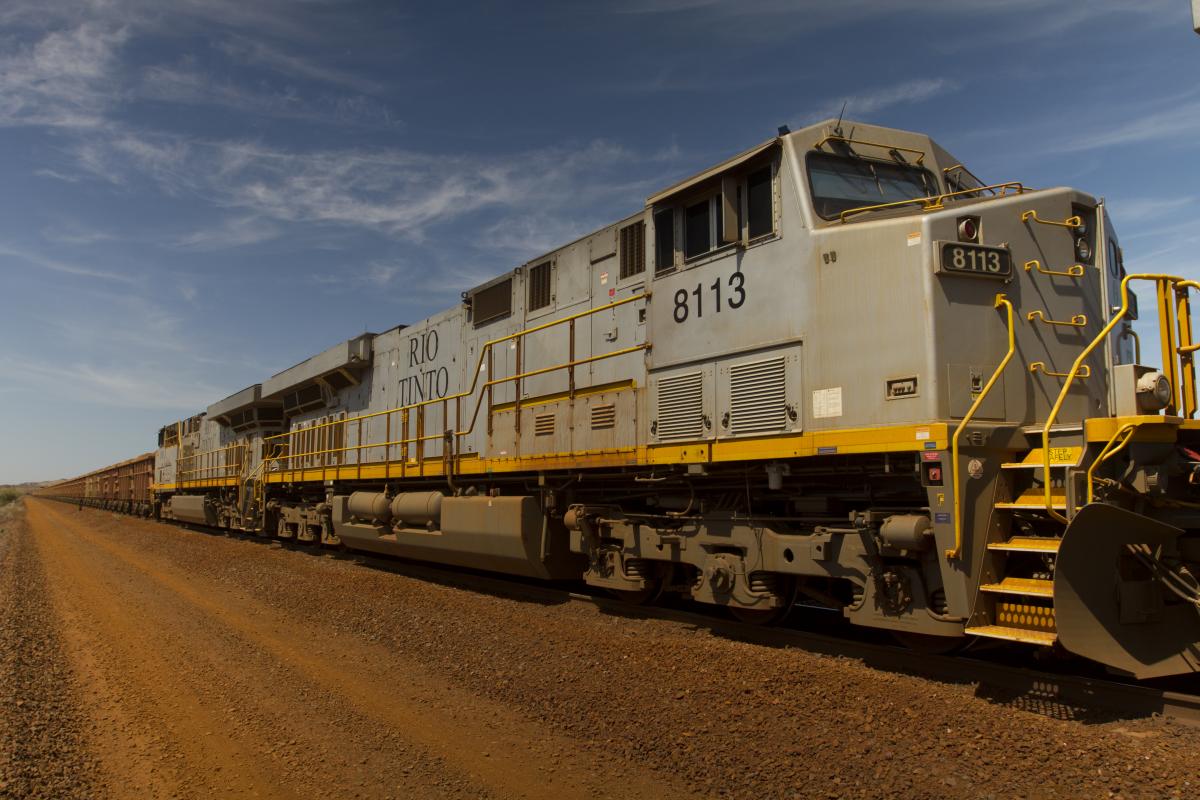  /><br />
<br />
They wind their way through gentle hills, carrying iron ore from remote mines like Rio Tinto’s Yandicoogina, 1350 kilometres from Perth, to towns and ports from where this precious red earth is shipped all over the world.<br />
<br />
Connecting this and 14 other remote mine sites operated by Rio Tinto in Western Australia is a rail network of more than 1500km of tracks which travel across the state’s massive expanse. Western Australia is vast, its land mass only slightly smaller than the entire Indian subcontinent, in fact &nbsp;if it were a country it would be tenth largest in the world.<br />
<br />
At the mine, massive trucks, roughly the height of a two story building operate around the clock to fill the cars carrying as much as 240 tonnes of iron ore from the mine site to the processing plant.<br />
<br />
In coming years the locomotives currently used throughout the Pilbara will be replaced by the next generation in transportation technology.<br />
<br />
&nbsp;