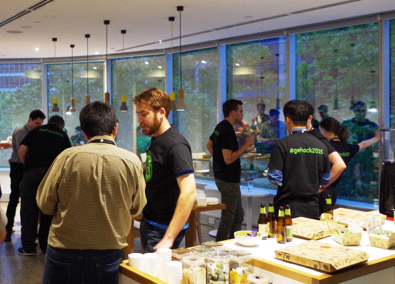 ><br />
<br />
<em>GE's Matt Cechner, transportation solutions consultant (second from left), keeps on mentoring over munchies during a well-earned break in the Industrial Hackathon proceedings.</em><br />
<br />
Late on Sunday afternoon, teams are kicking back with pizza and beer after presenting their ideas. The judges, having grilled each group on the commercial realities and finer technical points of their proposals, are in conference.<br />
<br />
The talk on the Hackathon floor dials down to silence as a microphone is handed to Cindy Nicholson, associate director, Optus/Singtel. On behalf of all the judges—Ian Gardiner from AWS, Kuba Tymula, CEO of Harris Partners, Prem Naraindas of Tata Consultancy Services, and Mark Sheppard—she congratulates the participants on their weekend’s work, before announcing the winners.<br />
<br />
<strong>And the grinners are ...</strong><br />
<br />
Team Paperless, which had spent the better part of Saturday debating which problem to tackle, takes first place with its solution for an automated audio system to help maintenance technicians on railways complete their tasks more confidently and efficiently. Their proposed product—”The Whisperer”— includes a bluetooth-enabled headset to communicate digitised maintenance instructions, and a smart glove enabled with posture and motion detection to register compliance and guide procedures.<br />
<br />
“It’s a cloud-based solution, rugged and industrial, especially for the environment that it’s in. There’s motion control, and data analytics for it. We can report the task start and finish times, we can decrease the task completion time and we can increase the reliability of the equipment,” explained team spokesperson Richard Bercich during the presentation. The group, consisting of Bercich, Victor Touron, Po Liu and Ran Peleg, each receive a Microsoft Surface 3 tablet computer. And, the money-can’t-buy part of the prize is that if they continue to develop their idea, they have the opportunity to be mentored through the process by GE CIO Australia & New Zealand, Mark Sheppard.<br />
<br />
In all, three teams tackled the “Automated audio system for rail maintenance” problem, and a different solution proposed by Team On Track—Tarun Mookhey, Michael Lucas, Eko Budiono Tedjo and Syed Sheece Raza Gardezi—wins second prize, $5,000 worth of Amazon Web Services. The group’s minimum viable prototype is made up of a voice-based interactive application programming interface (API), delivered by headset, and a web-based dashboard for management. For a theoretical company running 100 locomotives, Team On Track estimated it could save $5 million a year on maintenance costs, and also return 5.8 extra days of availability per locomotive per year.<br />
<br />
Niku Gorji and Gary Weng of Team Remote Safety take third prize, for their solution to ensure the safety of remote workers during an emergency or natural disaster. Consisting of a management console and smartphone app, it allows companies with a remotely dispersed workforce to report an incident (from the field or from a central headquarters), trigger an alert to all in the vicinity, manage response, report on the incident and analyse performance of the system. Gorji and Weng each received a Samsung Galaxy S6, courtesy of Optus.<br />
<br />
&nbsp;