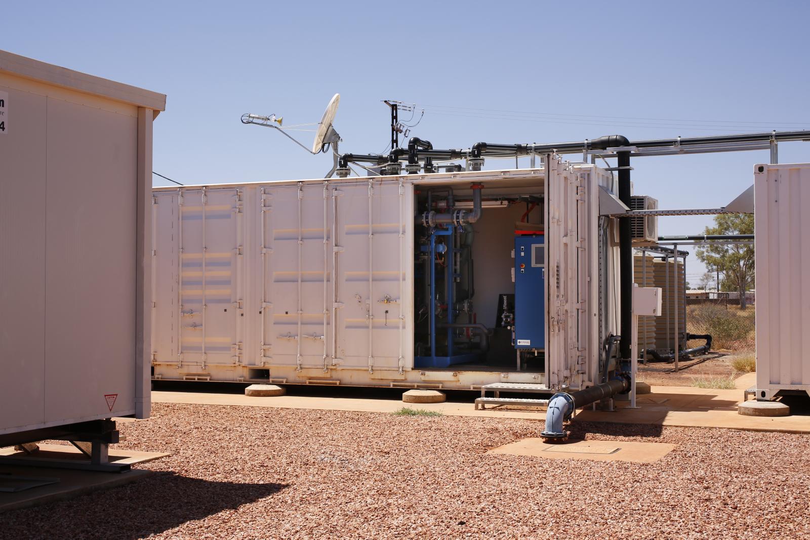  /><br />
<br />
<em>GE's Electrodialysis Reversal water-treatment systems are pre-assembled in shipping containers for trucking into remote environments.</em><br />
<br />
Water is precious in these communities of the Northern Territory’s arid south, so another major requirement of treatment proposals was high water recovery. Any purification process results in some water being drawn off with the extracted waste. Reverse-osmosis systems, for example, result in 20% to 35% water loss. GE’s EDR technology offers very high water recovery, typically removing only 4% to 10% of the treated water as concentrated brine. This lower volume of waste is also easier to safely dispose of.<br />
<br />
Most importantly, Hakim says that when the water in some communities was described as having “quirks”—salt, silica, nitrate and fluoride—he knew EDR, which draws salts from the water using an electrolytic process, would provide the perfect solution.<br />
<br />
After installation in 2013 it took some months to adjust the Northern Territory systems to onsite conditions; for example, much higher than expected temperatures of water flowing into the EDR systems required different ratios of pretreatment chemicals. At the same time, treated water began to flow. Bob Cullen, acting community coordinator at Ali Curung, sprinkled the council lawn with salt-free water, creating an oasis, and the communities’ gardens also got a greening. Cullen said the availability of fresh water prompted local elders’ plans to involve the area’s young men in horticultural projects, with the aim of helping their communities become more self-sufficient.<br />
<br />
Having entered their second year of operation, PWC’s EDR systems are now monitored remotely. Service staff, who used to make monthly expeditions to monitor results and train local Essential Service Operators, can log in from anywhere to assess the plants’ critical performance parameters, such as water flow, pressures, and quality. The data is managed by <a href=