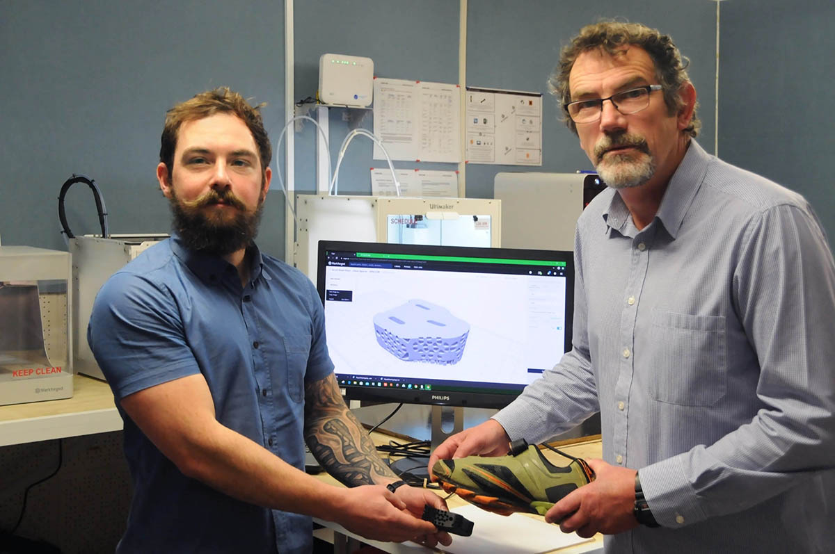 Martin Campbell and Ewan Conaghan stand in front of a computer image of their design