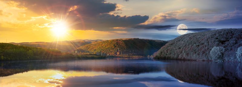 The sun and moon over a lake
